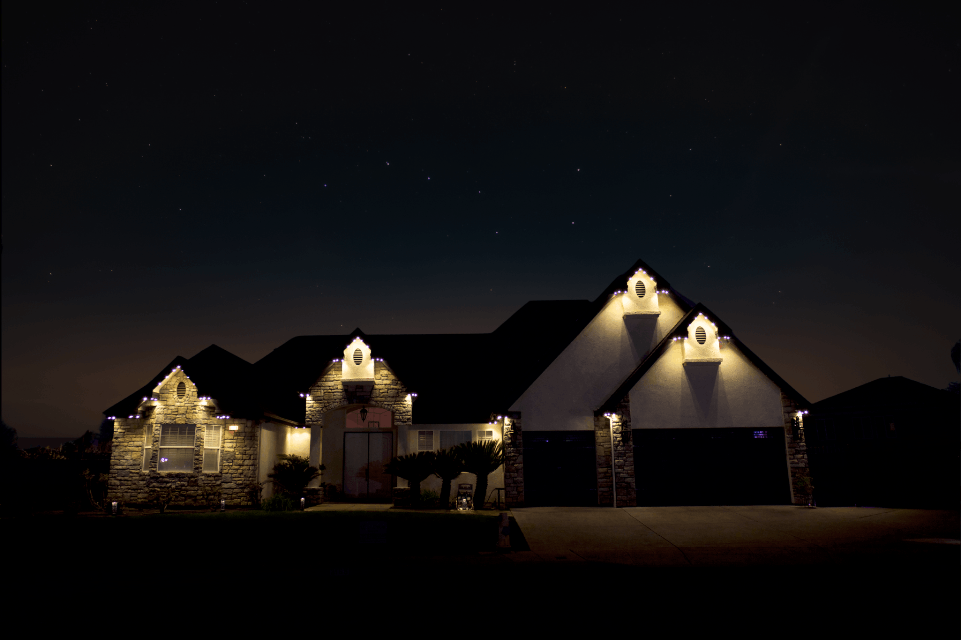 Stone-and-stucco home lit by bluEmber warm-white architectural downlights