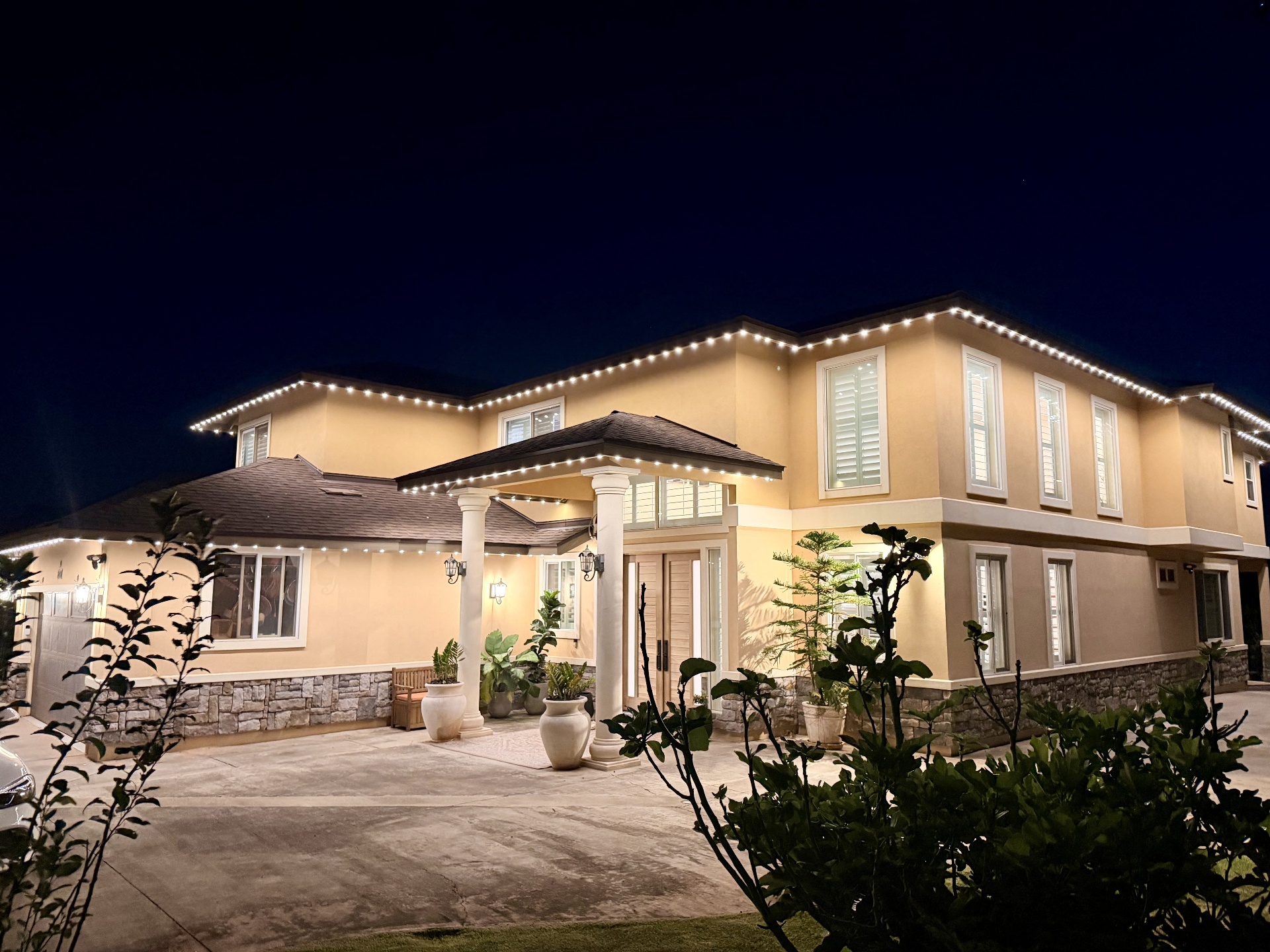 Two-story stucco home wrapped in warm-white bluEmber permanent roofline lighting