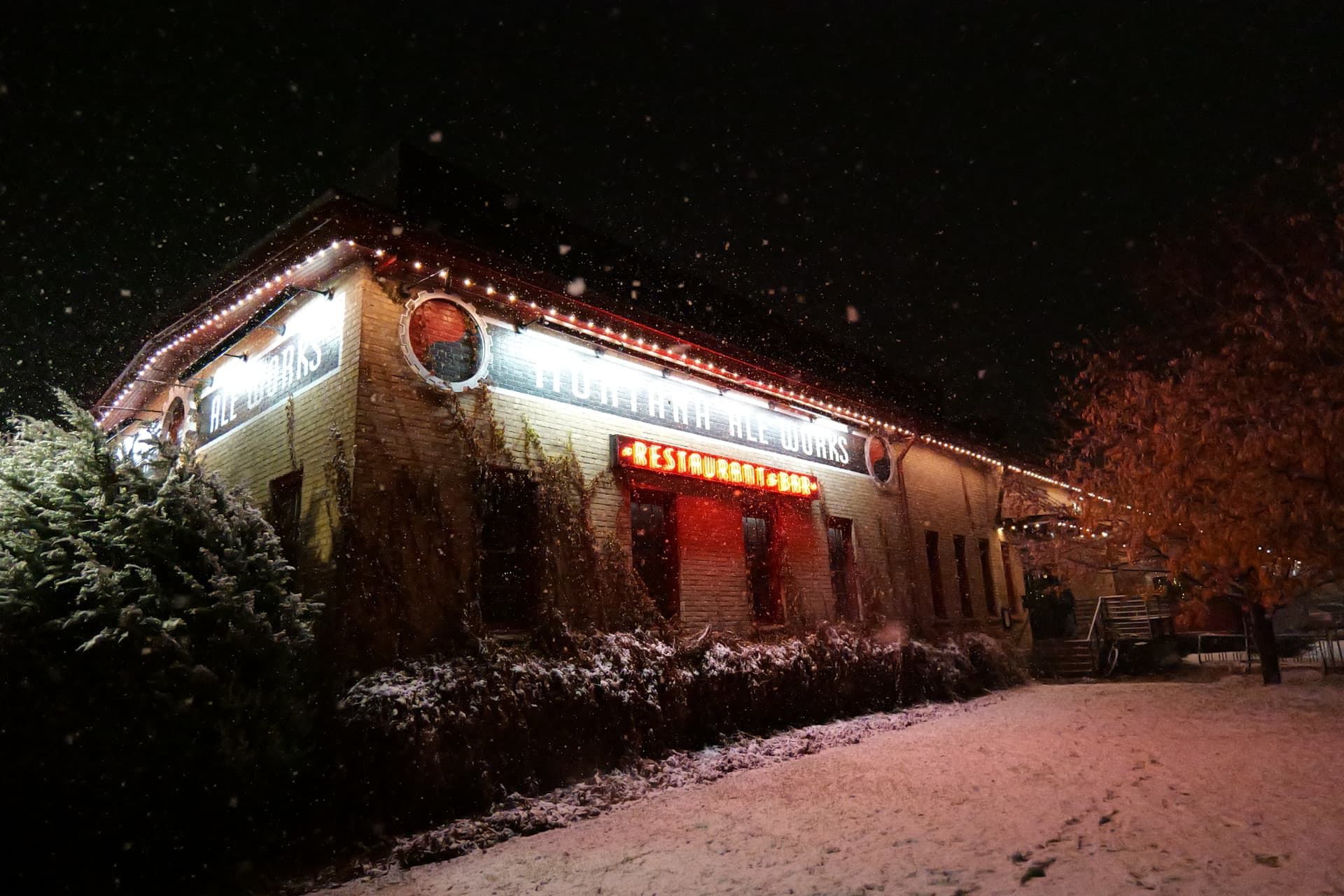 Restaurant and bar front glowing with warm-white bluEmber roofline lighting in falling snow