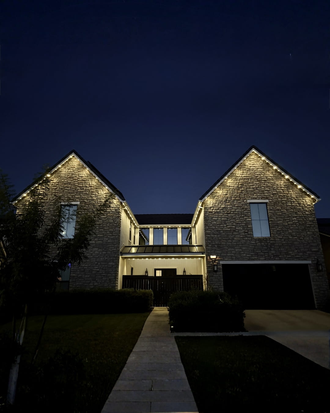 Twin stone gables lined in crisp warm-white bluEmber permanent lights
