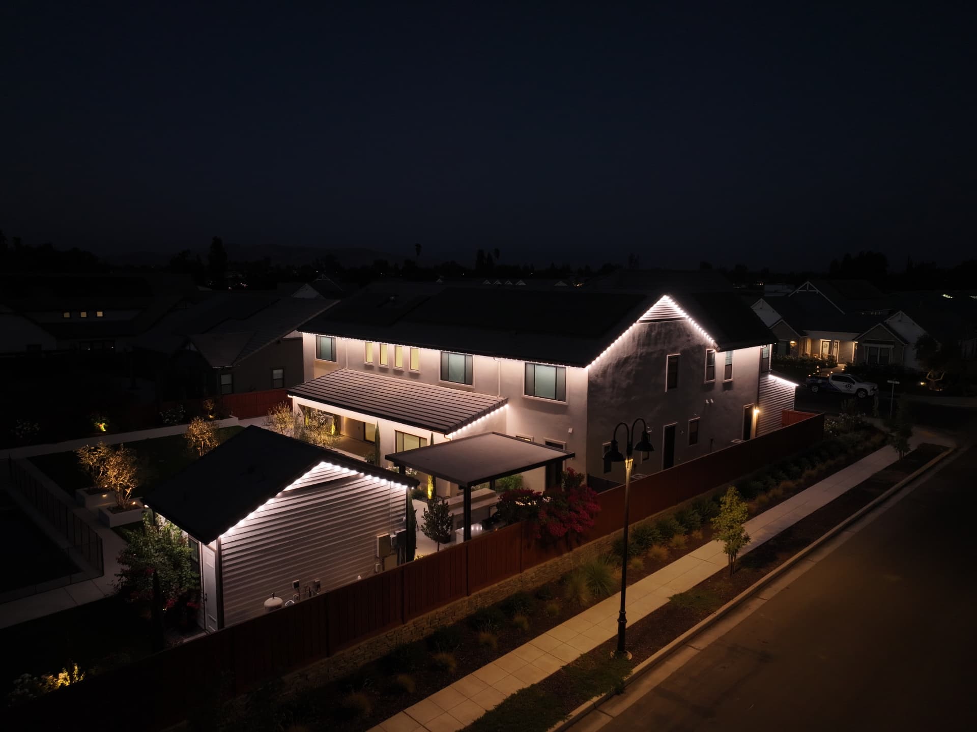 Aerial view of a two-story home in warm-white bluEmber lighting at dusk