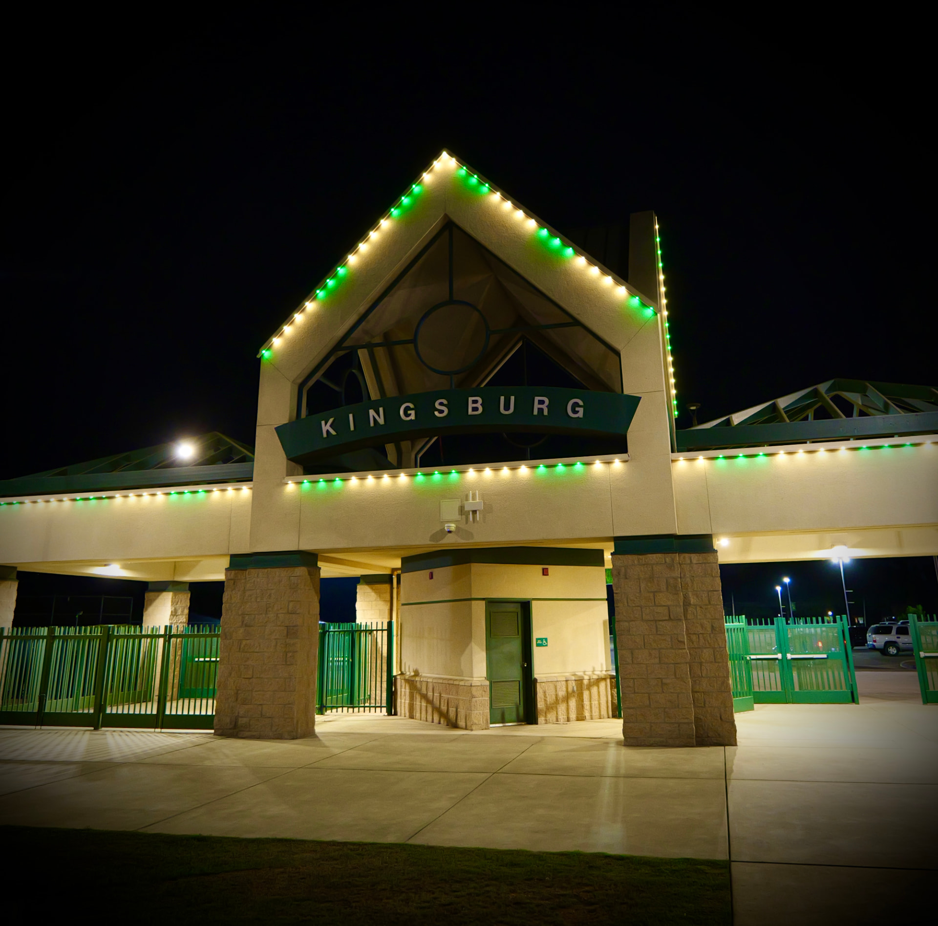 Kingsburg entrance pavilion outlined in alternating green and warm white lights at night