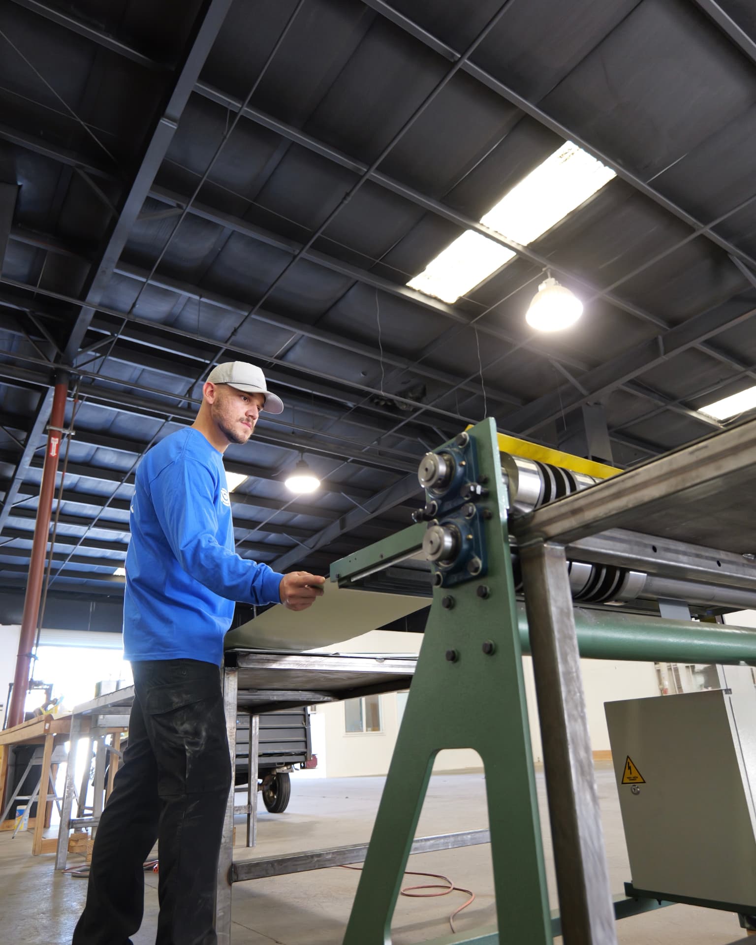 A bluEmber team member feeding aluminum channel stock through the forming machine at the Clovis facility