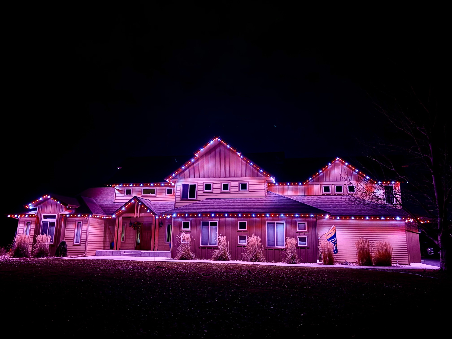 Montana home outlined in bluEmber red, white, and blue lights with a warm magenta wall wash