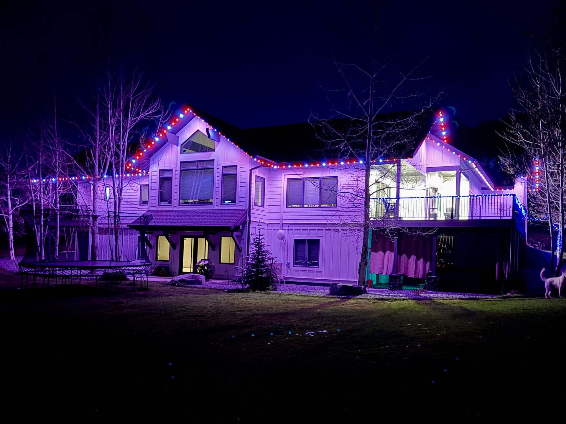 Mountain chalet with bluEmber red, white, and blue patriotic roofline lights washing the facade in purple