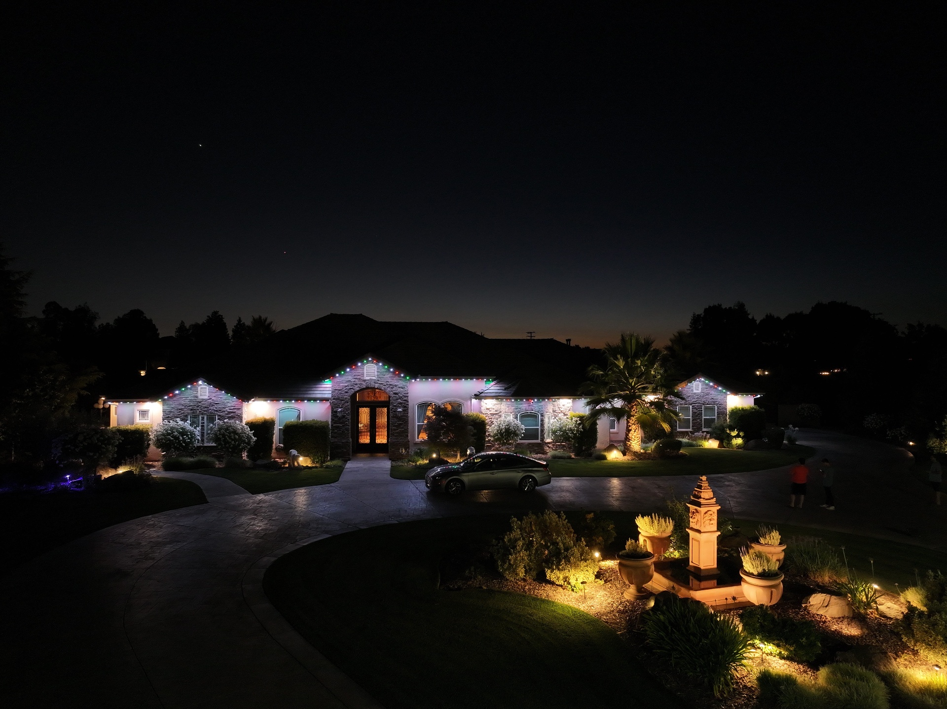 Aerial view of a home lit with red, green, and white bluEmber Christmas scene