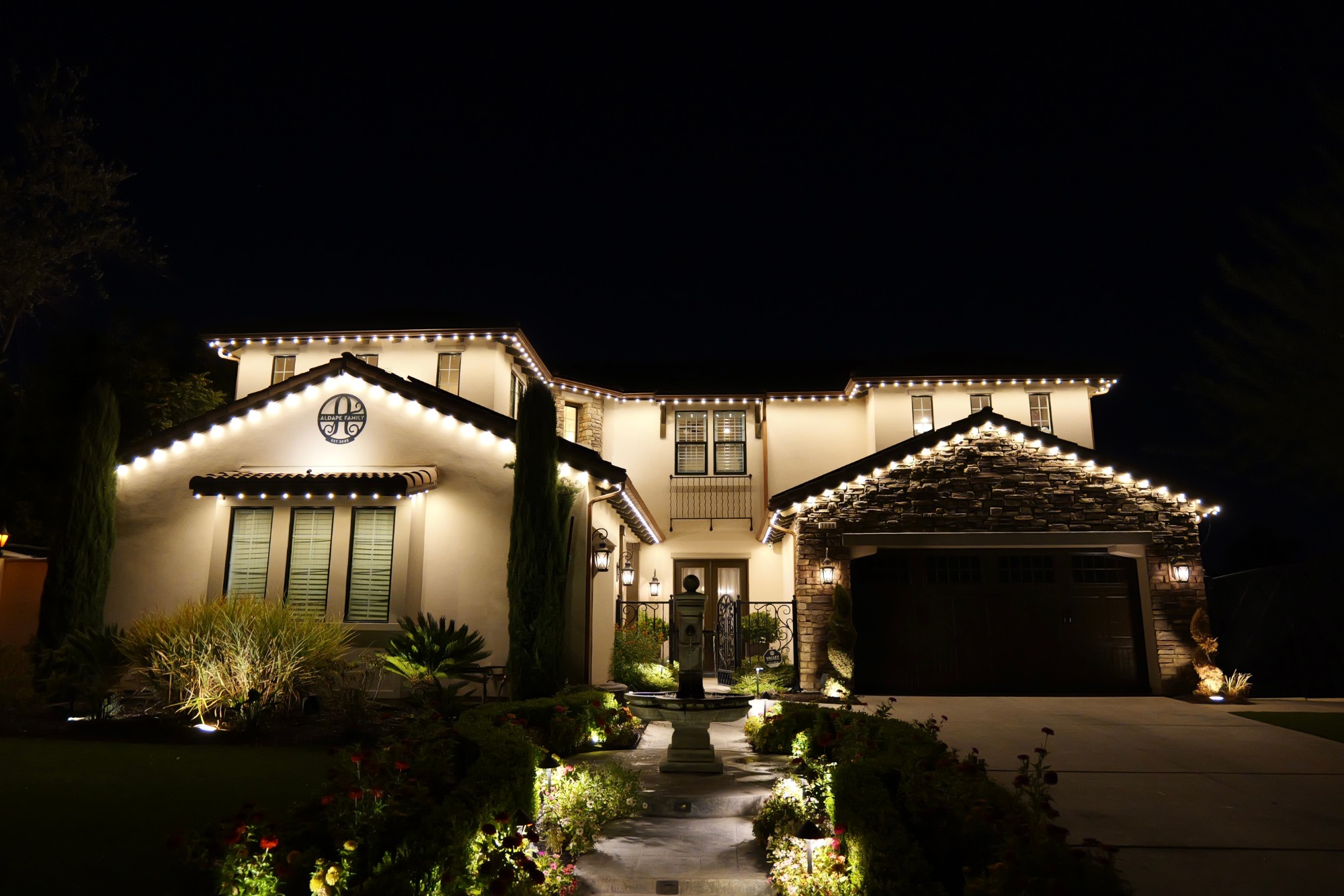 Two-story home at night with bluEmber permanent lighting along the roofline